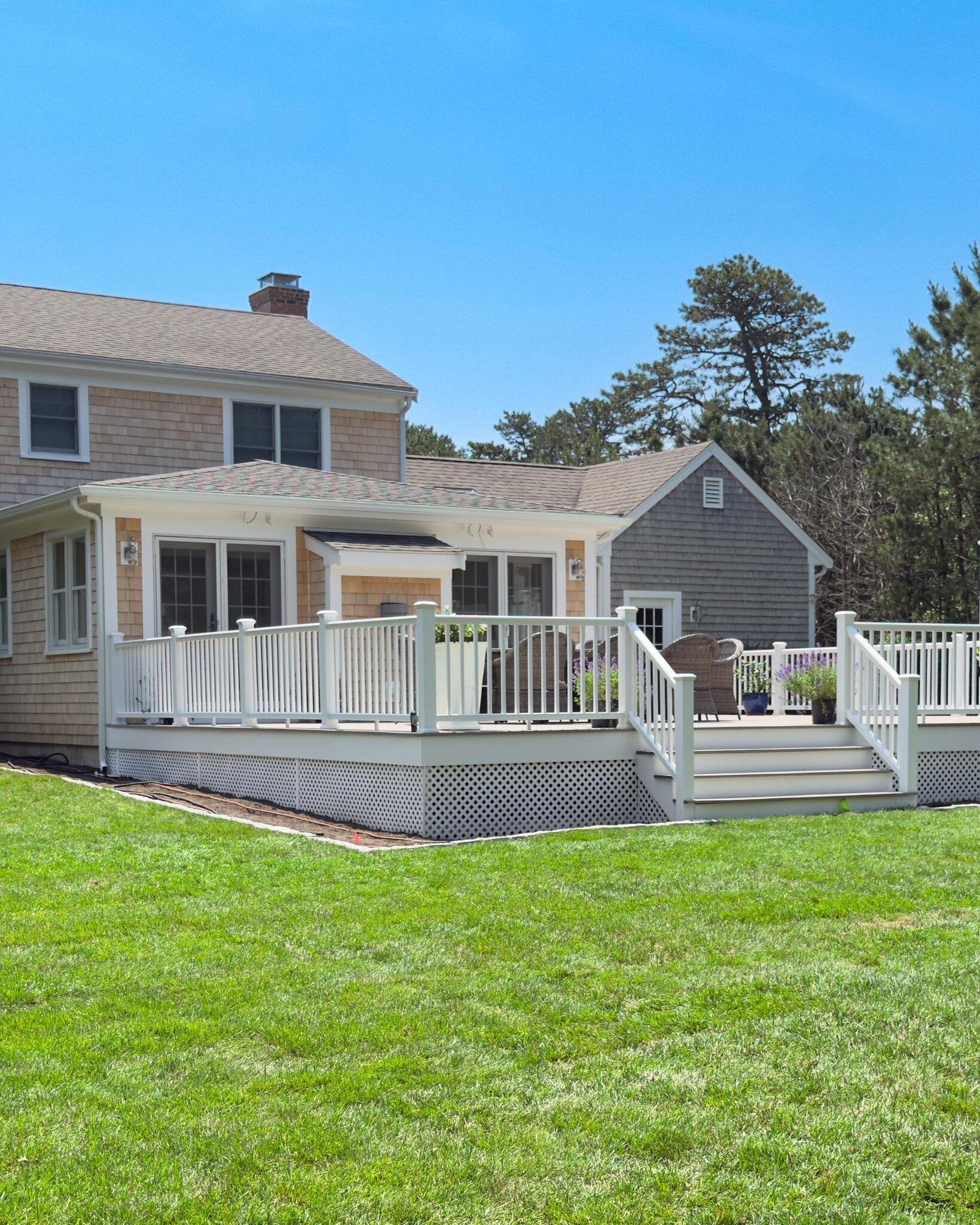 Multi-level deck with white railings built onto the rear of a Cape Cod home