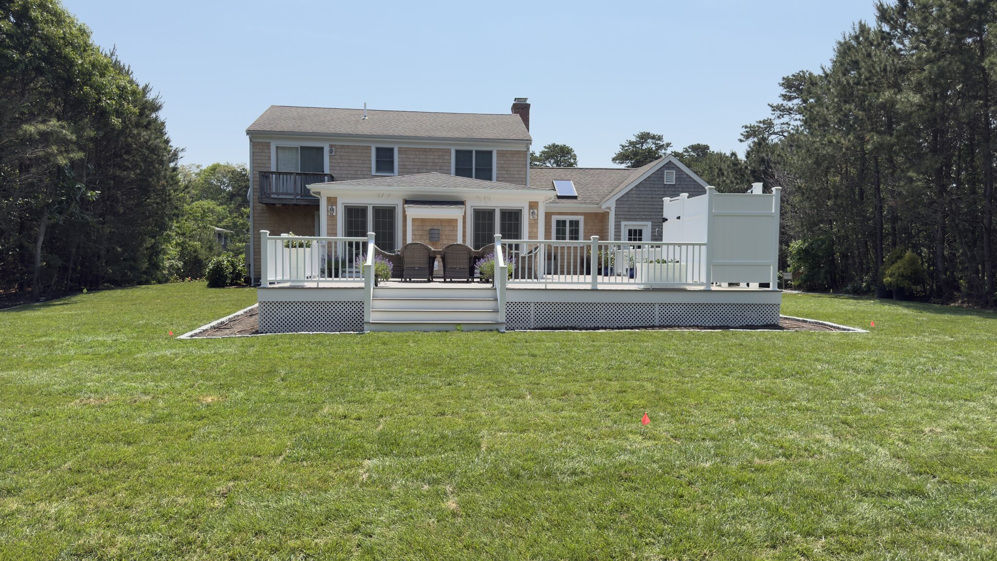 White-railed deck addition across the back of a Cape Cod shingle home