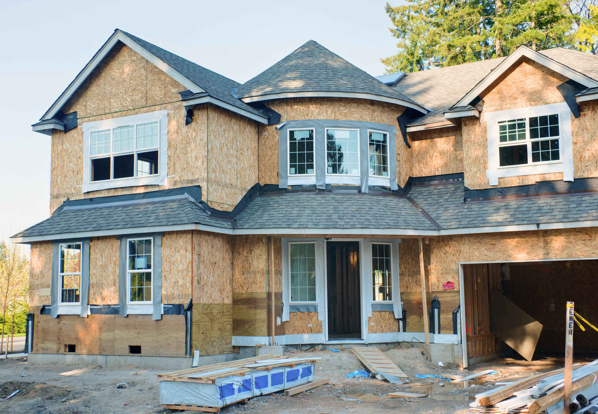 Two-story custom home under construction with sheathing and windows being installed