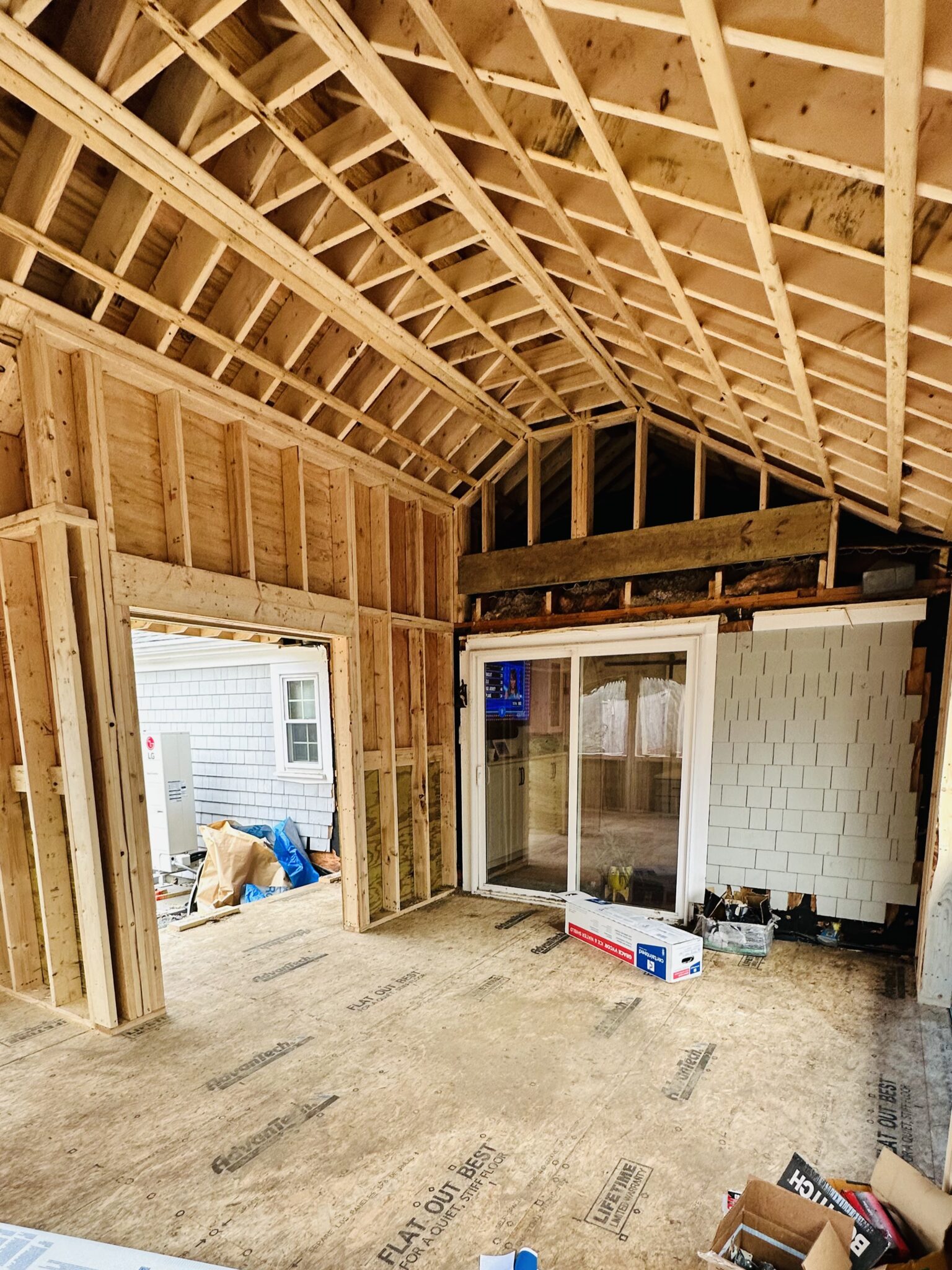 Room addition interior during framing with vaulted roof structure and new slider door